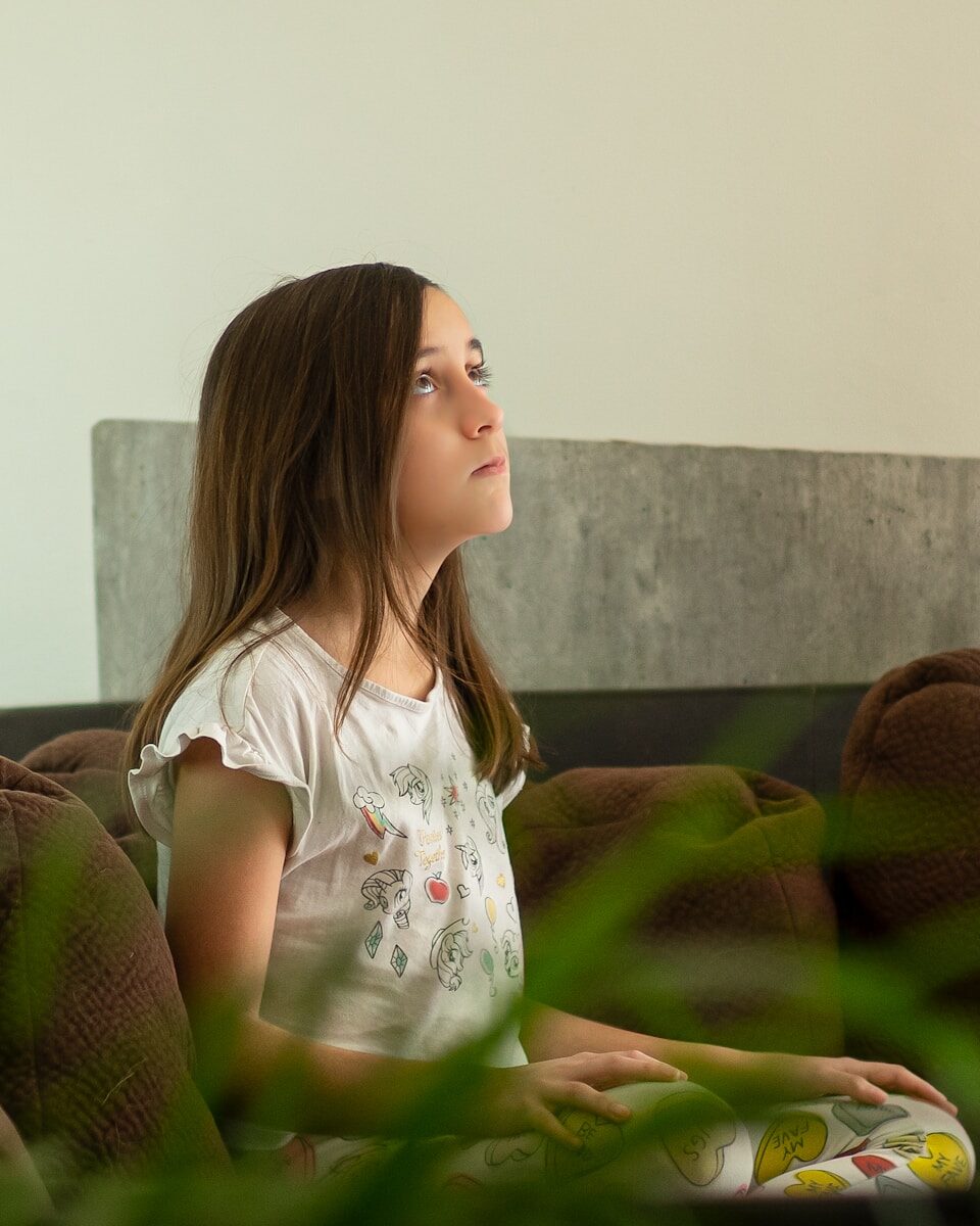 girl in white crew neck t-shirt sitting on green sofa
